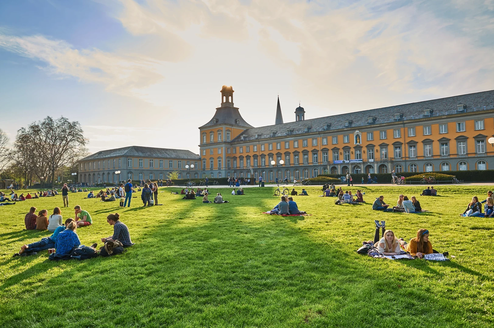 Eine Wissenschaftlerin und ein Wissenschaftler arbeiten hinter einer Glasfassade und mischen Chemikalien mit Großgeräten.